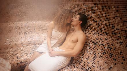 Beautiful young couple relaxing in spa at the spa center and kissing.