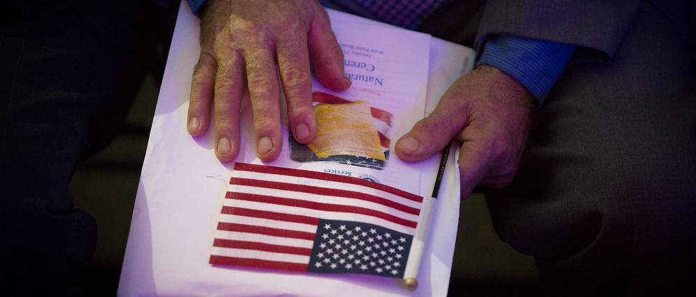Ein Einbürgerungsanwärter hält am 23.01.2018 in West Palm Beach (USA) seine Unterlagen und eine kleine US-Flagge. Die Regierung von US-Präsident Donald Trump verschärft die Kriterien zur Erlangung der amerikanischen Staatsbürgerschaft erneut. 