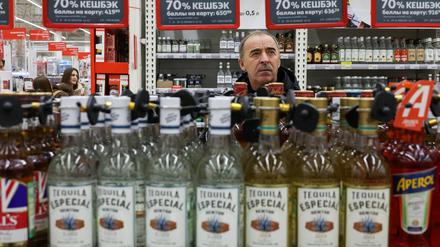 Ein Mann hinter einer Batterie von Alkoholflaschen in einem russischen Supermarkt.