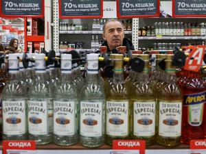 Ein Mann hinter einer Batterie von Alkoholflaschen in einem russischen Supermarkt.