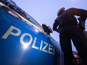Eine Polizistin steht neben einem Polizeifahrzeug.