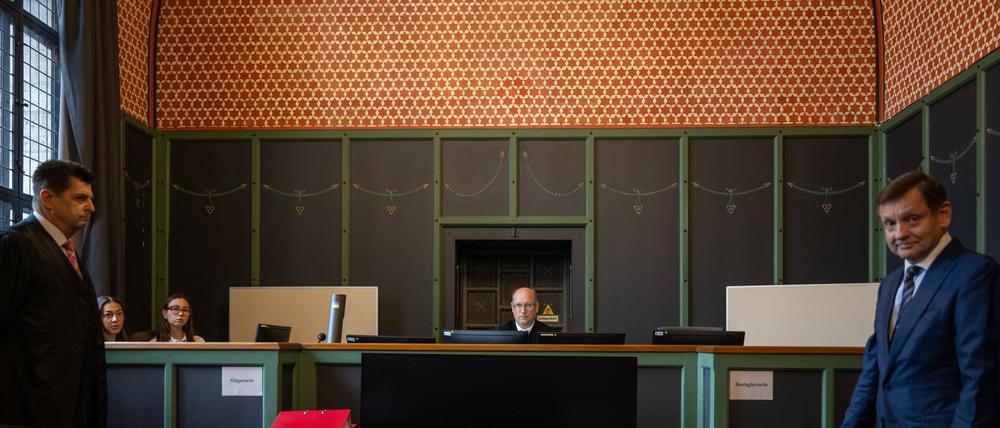 Burkhard Niebisch (M), Vorsitzender Richter, sitzt vor Beginn der Verhandlung über die Räumungsklage gegen die AfD im Saal 100 am Landgericht II auf seinem Platz. Rechts steht Kay Gottschalk, stellvertretender Bundessprecher der AfD vor Gericht, links der Anwalt der Immobilienfirma Quercus Grund GmbH.