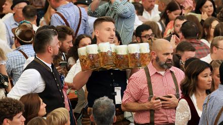 Schwerstarbeit: In einem Zelt des Oktoberfestes werden die ersten Biere an Besucher verteilt.