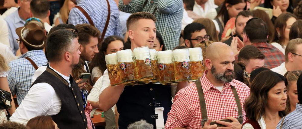 Schwerstarbeit: In einem Zelt des Oktoberfestes werden die ersten Biere an Besucher verteilt.
