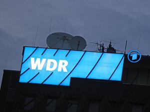 ARCHIV - 16.08.2022, Nordrhein-Westfalen, Köln: Ein Logo des WDR (Westdeutscher Rundfunk) leuchtet auf dem Dach des Senders.