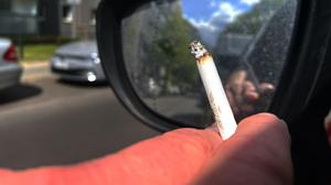 Eine Person raucht eine Zigarette beim Autofahren.