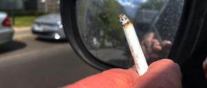 Eine Person raucht eine Zigarette beim Autofahren.