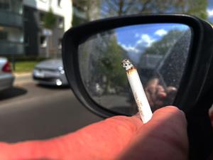 Eine Person raucht eine Zigarette beim Autofahren.