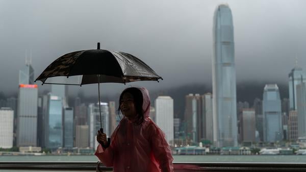 Ein Mädchen hält auf diesem Archivfoto einen Regenschirm in Tsim Sha Tusi vor dem Victoria Harbor und der Skyline von Hongkong.  