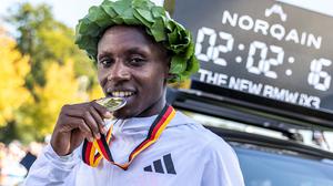 Sabastian Sawe aus Kenia beißt nach dem Sieg beim Berlin Marathon 2025 auf seine Medaille.