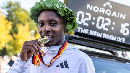 Sabastian Sawe aus Kenia beißt nach dem Sieg beim Berlin Marathon 2025 auf seine Medaille.