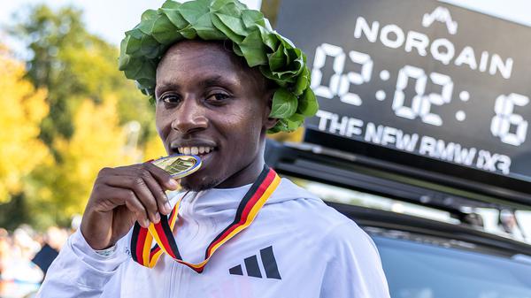 Sabastian Sawe aus Kenia beißt nach dem Sieg beim Berlin Marathon 2025 auf seine Medaille.