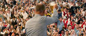 21.09.2025, Bayern, München: Bundeskanzler Friedrich Merz (CDU) prostet bei seinem Besuch des 190. Oktoberfest, auf Einladung von Bayerns Ministerpräsident Söder (CSU), mit einem Bierkrug den hunderten Bierzeltbesuchern von der Empore in der Festhalle Schottenhamel zu.