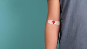 Illustration: Auf einem Arm klebt ein Pflaster mit Herzchen-Motiv.
