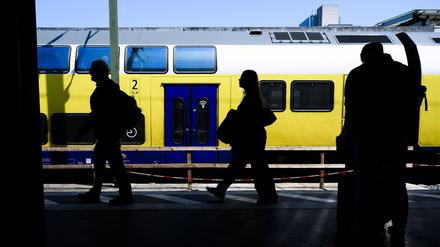Die Silhouetten von Fahrgästen zeichnen sich vor einem Regionalzug ab.