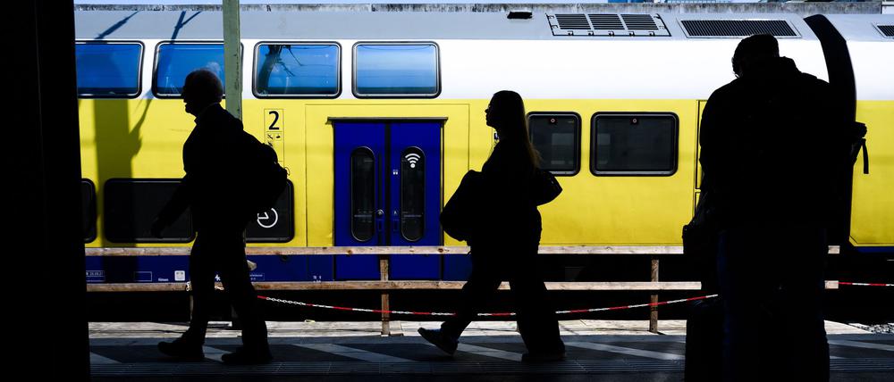 Die Silhouetten von Fahrgästen zeichnen sich vor einem Regionalzug ab. 
