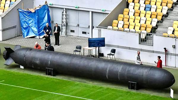 Menschen stehen neben einer TLK-Unterwasserdrohne, die auf einer Militär-Expo in Lviv präsentiert wird (September 2025).