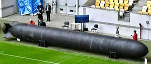 Menschen stehen neben einer TLK-Unterwasserdrohne, die auf einer Militär-Expo in Lviv präsentiert wird (September 2025).