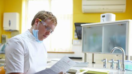 Ein Zahnarzt schaut auf Papier.