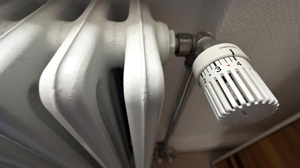 Ein alter Heizkörper mit großen Rippen und einem analogen Thermostat. 