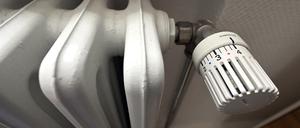 Ein alter Heizkörper mit großen Rippen und einem analogen Thermostat. 