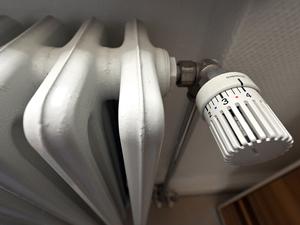 Ein alter Heizkörper mit großen Rippen und einem analogen Thermostat. 