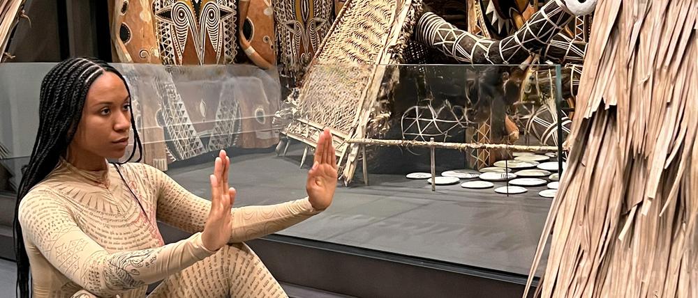 Performance-Künstlerin Kristy Nataraja mit einer Performance vor einem Häuserkubus aus Papua-Neuguinea.