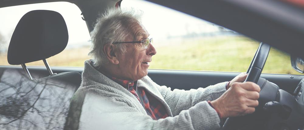 Ein alter Mann sitzt im Auto am Steuer. (Symbolbild)