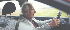 Ein alter Mann sitzt im Auto am Steuer. (Symbolbild)
