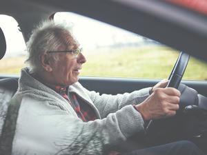 Ein alter Mann sitzt im Auto am Steuer. (Symbolbild)