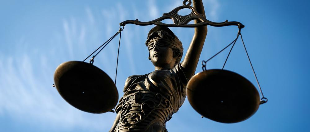 Eine Statue der Justitia hält eine Waage in der Hand.
