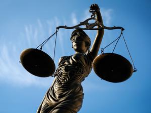 Eine Statue der Justitia hält eine Waage in der Hand.