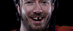 Ein Eishockeyspieler gibt den Blick frei auf zwei fehlende Schneidezähne. 