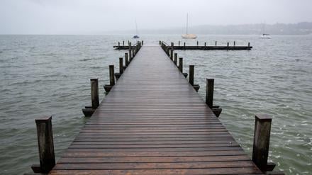 Dunkle Wolken ziehen über einen Steg am Starnberger See. 