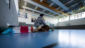 Ein Student sitzt 2024 in Münster zum Wintersemesterbeginn in einer Turnhalle auf einer Isomatte. 