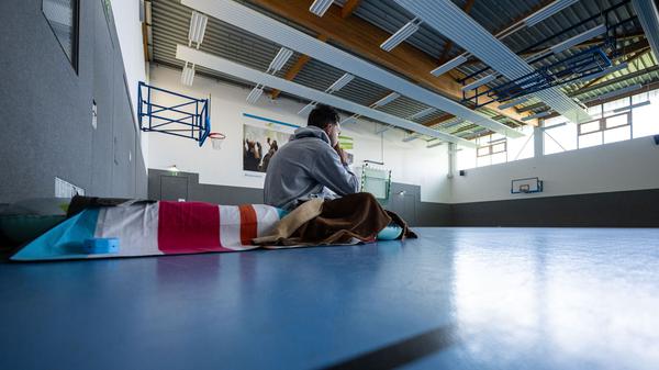 Ein Student sitzt 2024 in Münster zum Wintersemesterbeginn in einer Turnhalle auf einer Isomatte. 