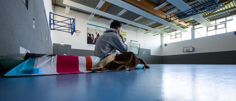 Ein Student sitzt 2024 in Münster zum Wintersemesterbeginn in einer Turnhalle auf einer Isomatte. 