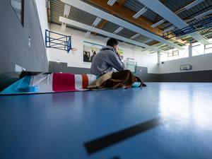 Ein Student sitzt 2024 in Münster zum Wintersemesterbeginn in einer Turnhalle auf einer Isomatte. 