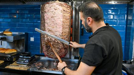 Ein Mann schneidet Fleisch von einem Döner-Spieß.
