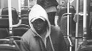 Ein Mann mit weißer Kapuze ist in einem Mittelgang eines Busses zu sehen. (Foto einer Überwachungskamera)