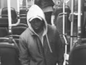Ein Mann mit weißer Kapuze ist in einem Mittelgang eines Busses zu sehen. (Foto einer Überwachungskamera)