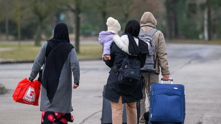 Migranten verlassen mit Reisegepäck das Gelände der Zentralen Ausländerbehörde Brandenburgs (ZABH).