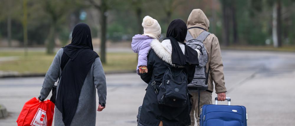 Migranten verlassen mit Reisegepäck das Gelände der Zentralen Ausländerbehörde Brandenburgs (ZABH).