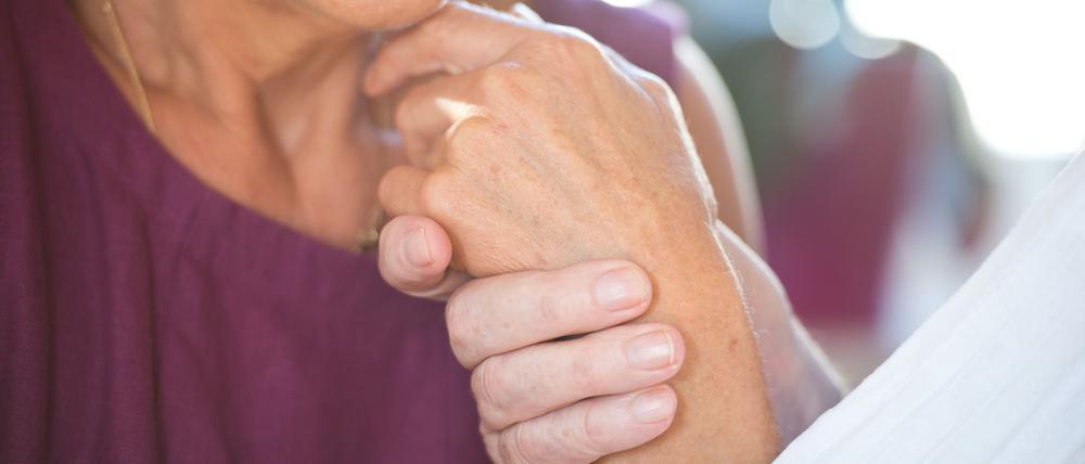 Eine Frau hält die Hand ihres an Demenz erkrankten Mannes.