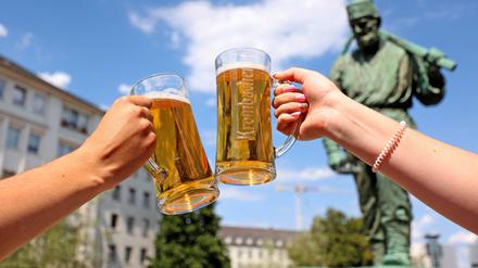 Zwei Menschen stoßen mit Biergläsern an. 