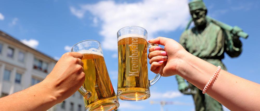 Zwei Menschen stoßen mit Biergläsern an.