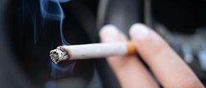 Eine Frau sitzt in einem Pkw und hält eine Zigarette (Symbolbild).