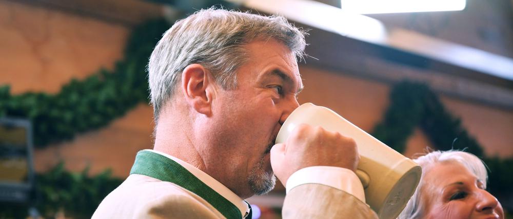 Markus Söder (CSU), Ministerpräsident von Bayern, trinkt nach dem Anstich im Schottenhammel-Festzelt neben seiner Frau Karin Baumüller-Söder aus einem Bierkrug (Symbolbild).