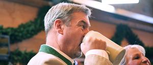Markus Söder (CSU), Ministerpräsident von Bayern, trinkt nach dem Anstich im Schottenhammel-Festzelt neben seiner Frau Karin Baumüller-Söder aus einem Bierkrug (Symbolbild).
