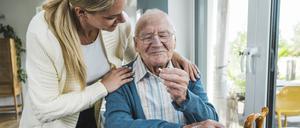 Eine Frau hilft einem älteren Mann bei der Einnahme von Medikamenten.